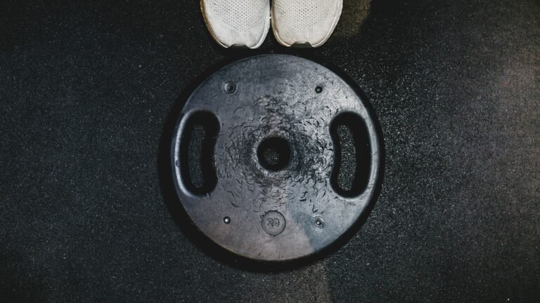 White running shoes beside a black weight plate, representing combined endurance and strength training