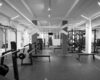 Barbell benches and weight plates in a gym, with resistance machines visible behind them.