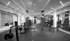 Barbell benches and weight plates in a gym, with resistance machines visible behind them.