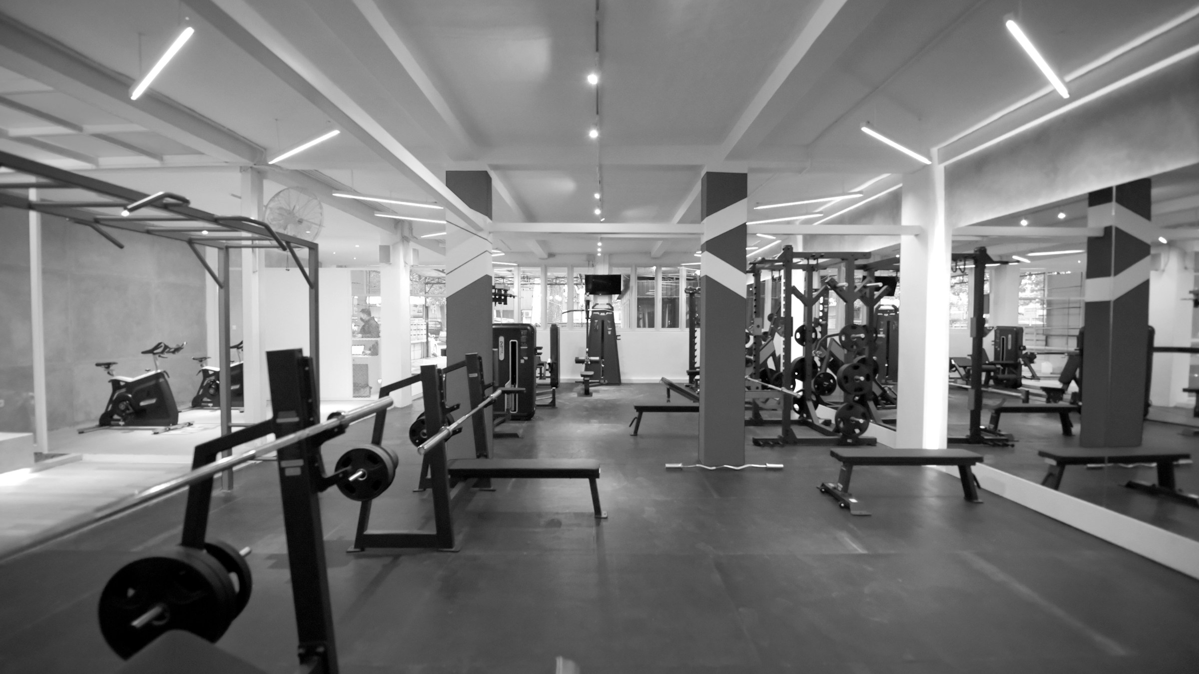 Barbell benches and weight plates in a gym, with resistance machines visible behind them.