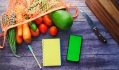 Fresh vegetables beside a notebook and phone used for planning a structured diet break