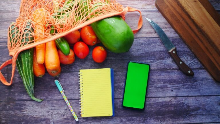 Fresh vegetables beside a notebook and phone used for planning a structured diet break