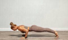 An adult yoga teacher demonstrating Chaturanga Dandasana on a mat