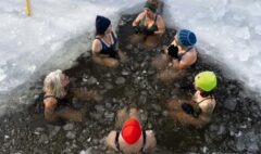 A group of adults taking part in supervised cold-water immersion in an ice opening.