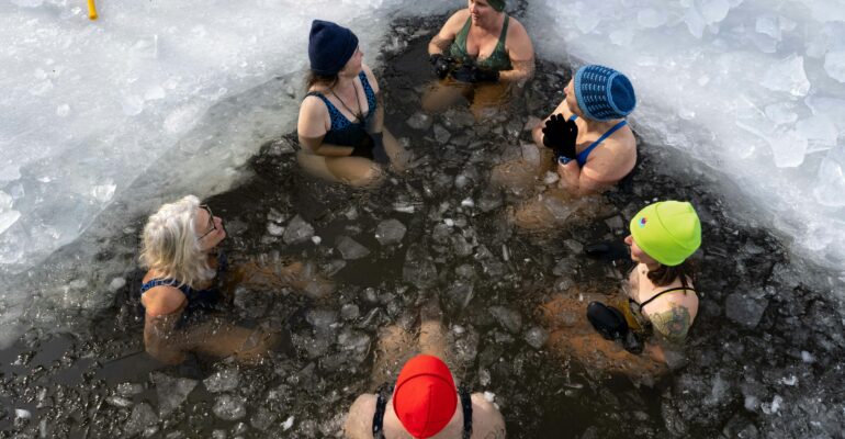 A group of adults taking part in supervised cold-water immersion in an ice opening.