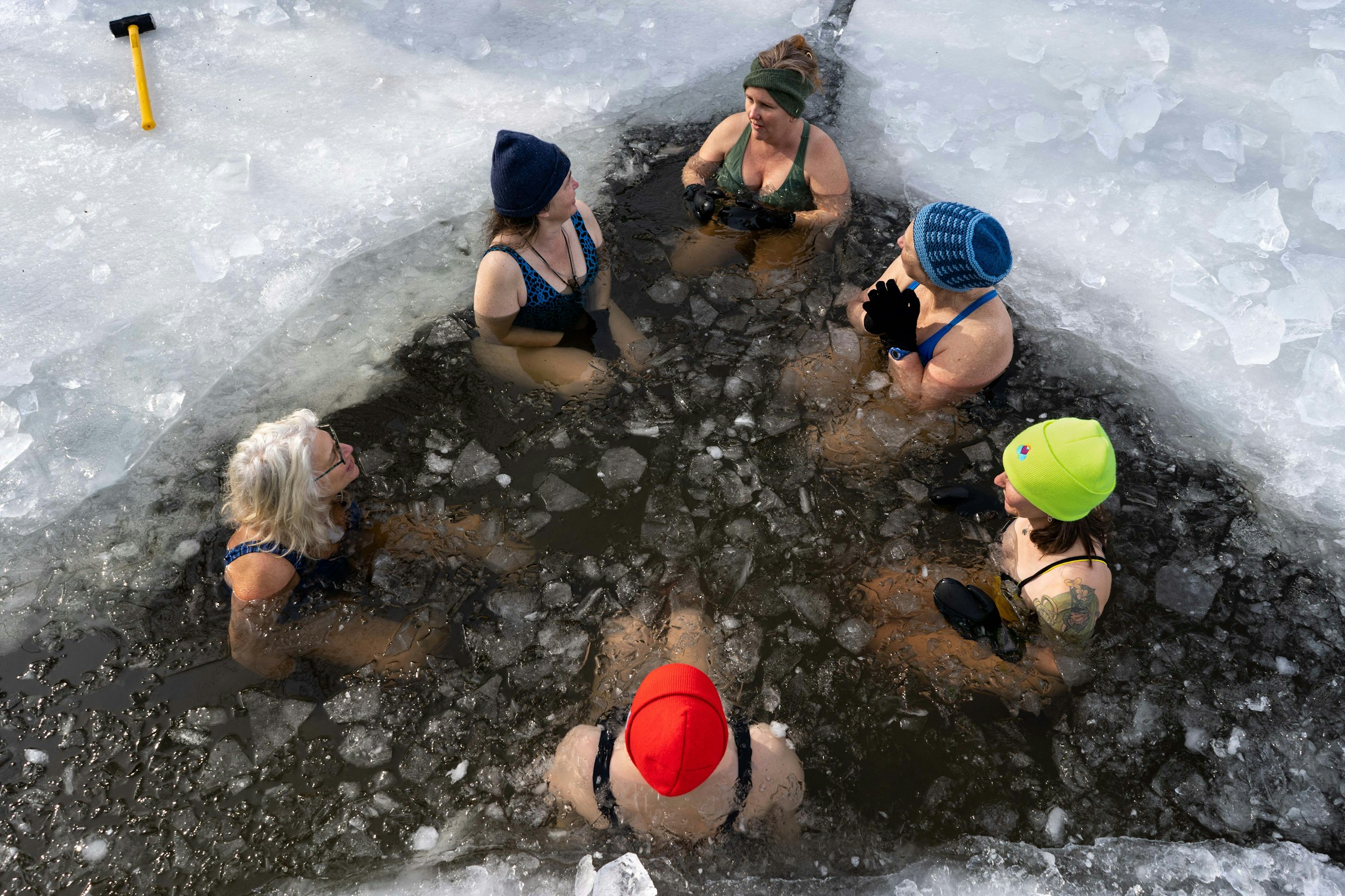 A group of adults taking part in supervised cold-water immersion in an ice opening.