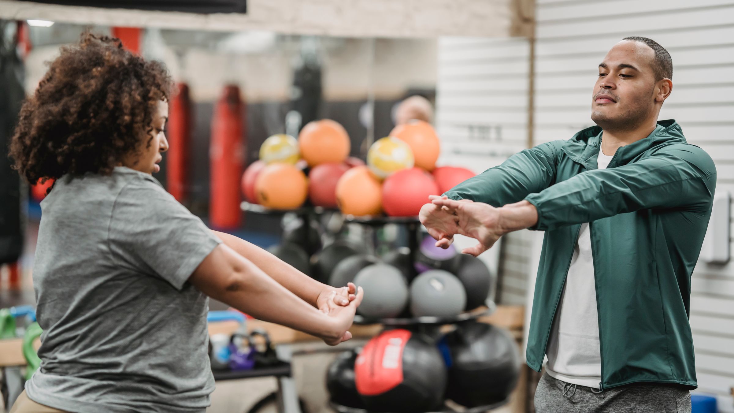 Adult client and fitness professional completing a standing warm-up in a gym