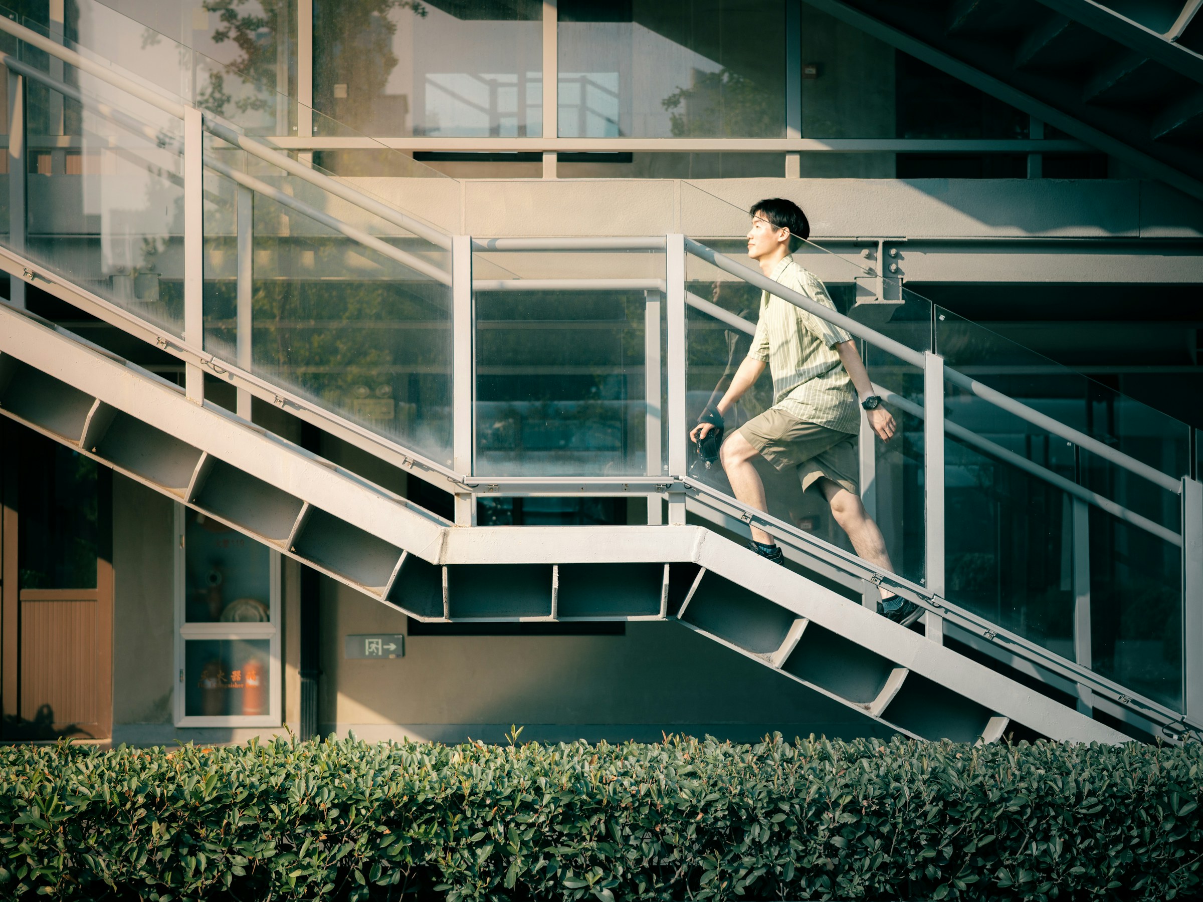 An adult climbing an outdoor staircase beside a modern building during the day.