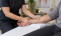 Massage therapist applying hands-on treatment to a client on a therapy table