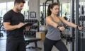 Certified personal trainer guiding a client in a gym
