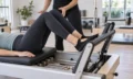 Pilates student training on a reformer machine in a studio