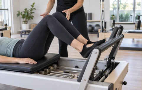 Pilates student training on a reformer machine in a studio