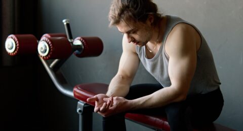 An adult exerciser sitting on a gym bench during a rest interval.