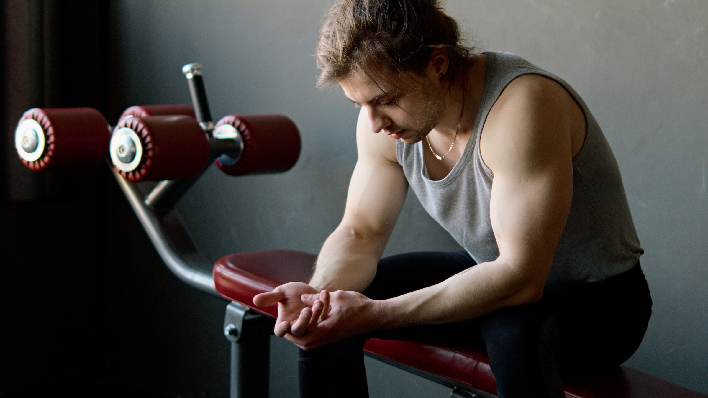 An adult exerciser sitting on a gym bench during a rest interval.