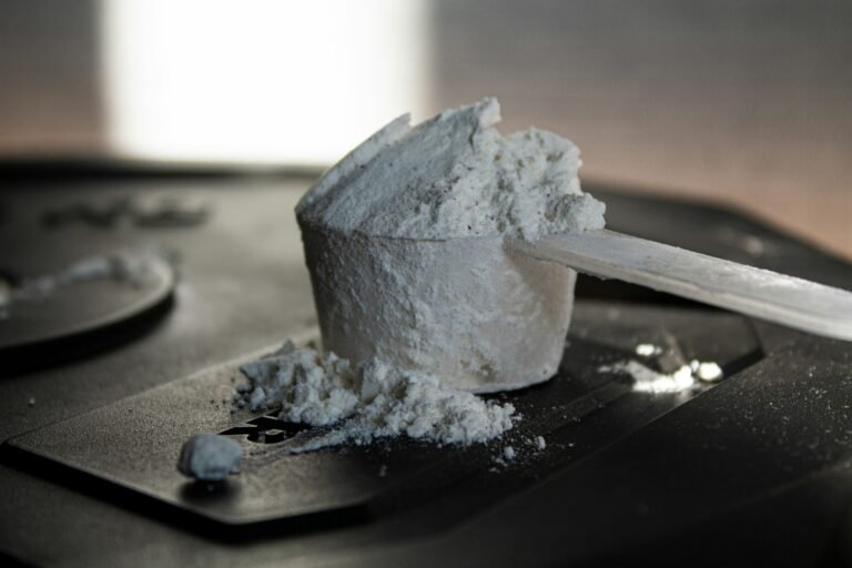 An unlabelled scoop of supplement powder on a dark surface, representing uncertainty about supplement contents.