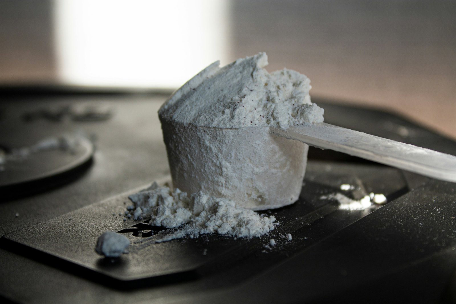 An unlabelled scoop of supplement powder on a dark surface, representing uncertainty about supplement contents.