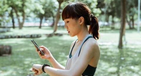 Adult runner checking a fitness tracker and smartphone after outdoor exercise