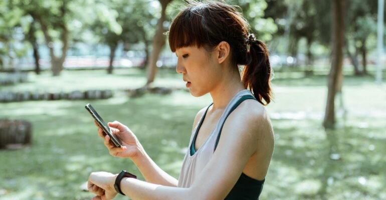 Adult runner checking a fitness tracker and smartphone after outdoor exercise