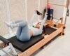 Woman exercising with straps on a wooden Pilates Reformer