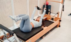 Woman exercising with straps on a wooden Pilates Reformer