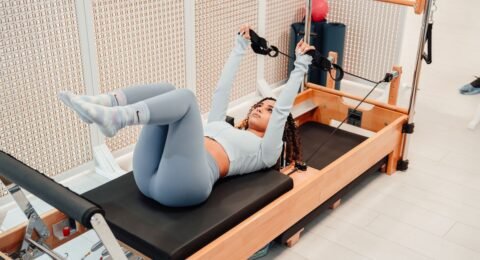 Woman exercising with straps on a wooden Pilates Reformer