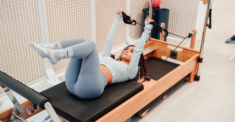 Woman exercising with straps on a wooden Pilates Reformer