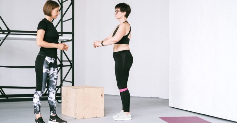 Older woman exercising beside a fitness instructor