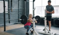 Personal trainer coaching an adult through a controlled front squat