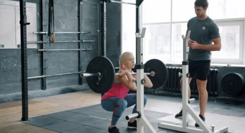 Personal trainer coaching an adult through a controlled front squat