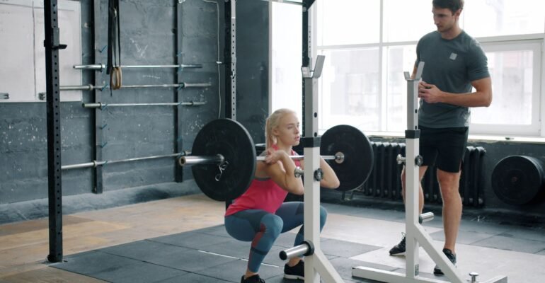 Personal trainer coaching an adult through a controlled front squat