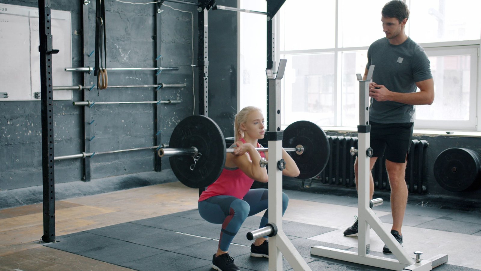 Personal trainer coaching an adult through a controlled front squat