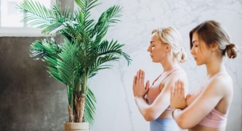 Yoga instructor guiding an adult through gentle slow breathing in a calm studio