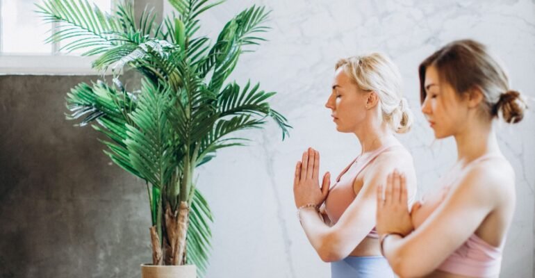 Yoga instructor guiding an adult through gentle slow breathing in a calm studio