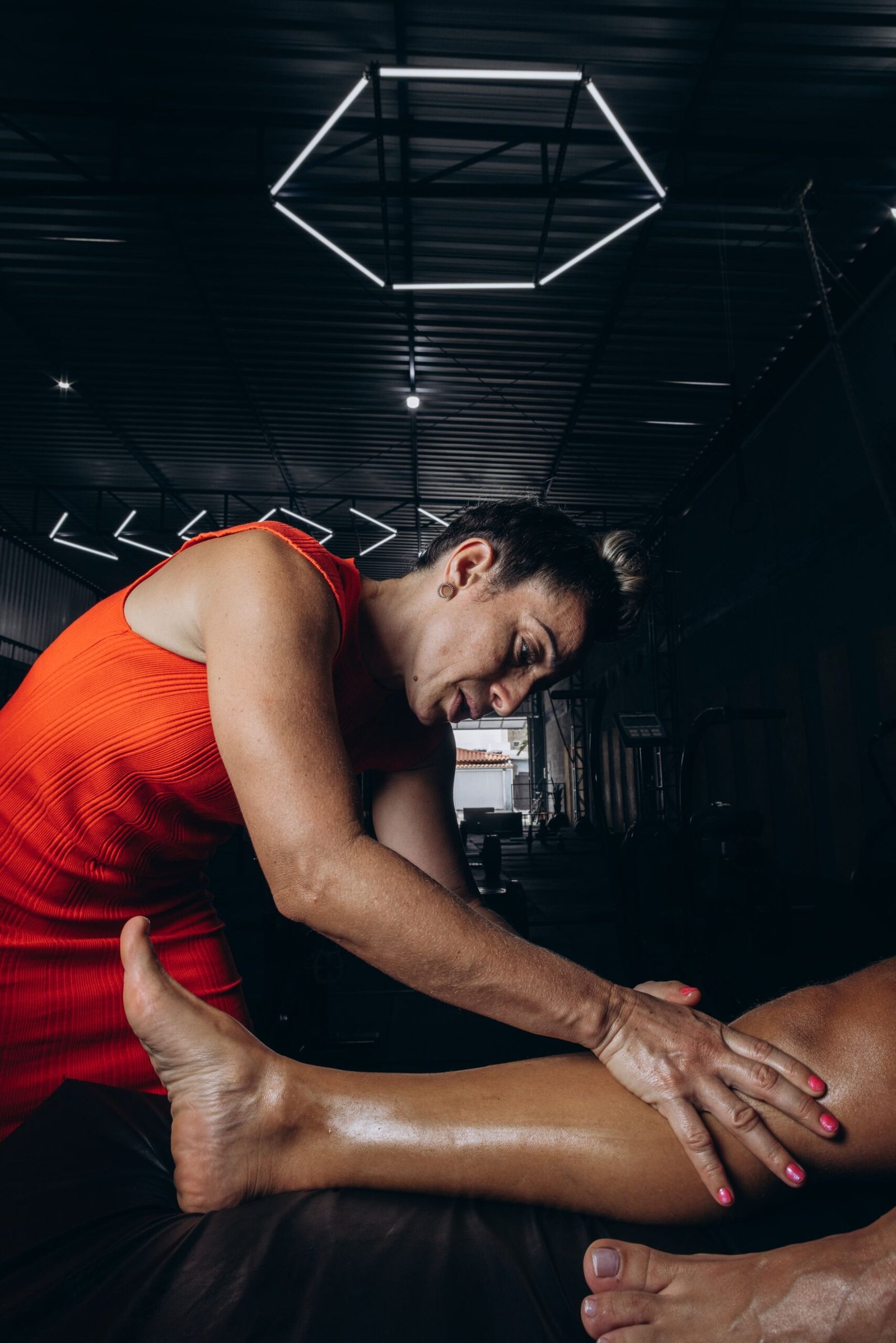 Sports massage practitioner working on an adult athlete’s leg after training