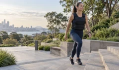 An adult walking uphill outdoors while wearing an evenly fitted weighted vest