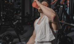 Exerciser wiping sweat with a towel and holding water after a workout