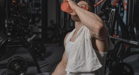 Exerciser wiping sweat with a towel and holding water after a workout