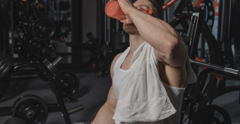 Exerciser wiping sweat with a towel and holding water after a workout
