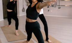 Three adults holding a standing yoga pose together in a bright studio