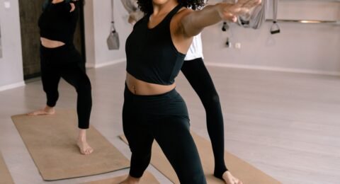 Three adults holding a standing yoga pose together in a bright studio