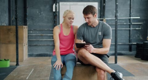Personal trainer and client discussing a structured exercise plan in a gym