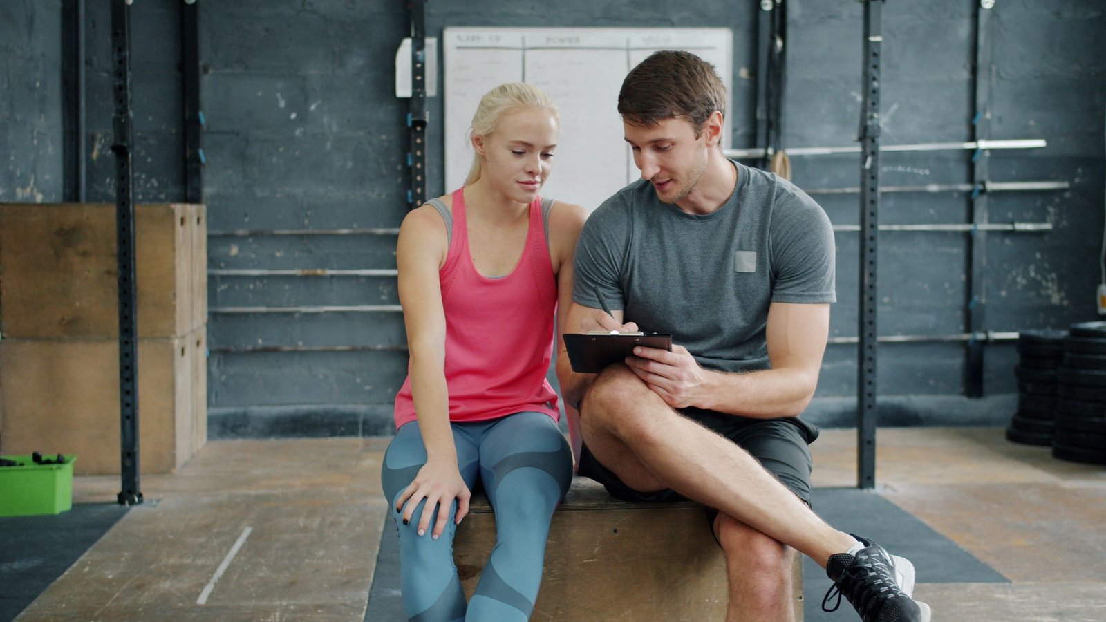 Personal trainer and client discussing a structured exercise plan in a gym
